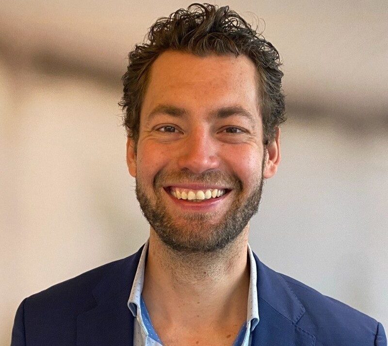 Geschäftliches Porträtfoto von Tobias Roth mit offenem Hemdkragen und freundlichem Ausdruck.